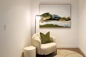 Una habitación con un sillón individual, una lámpara de pie y un cuadro en la pared.