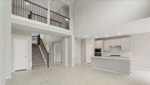 Ein geräumiges, zweistöckiges Haus mit moderner Küche, einer Treppe und einem großzügigen, offenen Wohnbereich.