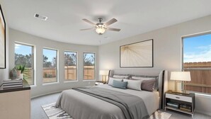 Ein Schlafzimmer mit einem großen Bett, einem Deckenventilator, einem Nachttisch und einem Fenster mit Blick auf den Garten.