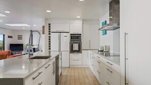 Une cuisine moderne avec des meubles blancs, des appareils en acier inoxydable et un grand îlot central.