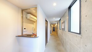 En modern hotellkorridor med en receptionsdisk, en luftkonditioneringsanläggning och inramade tavlor på väggarna.