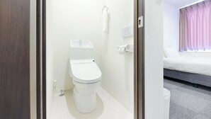 Ett modernt badrum med en toalett, en handduk som hänger på väggen och en synlig kontrollpanel.