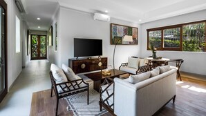 Uma sala de estar moderna com sofá, cadeiras, televisão e mesa de jantar.