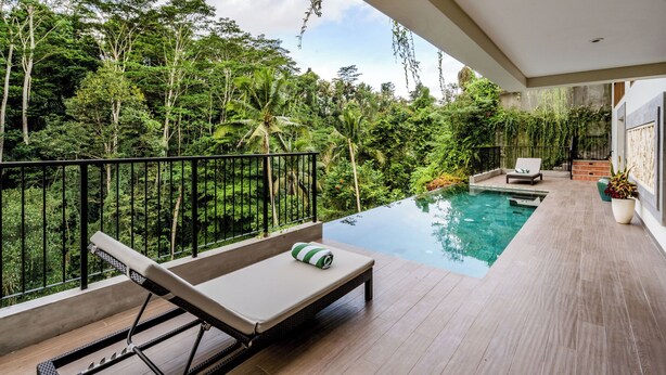 Un balcon avec une piscine, des chaises longues et une vue sur une végétation luxuriante.