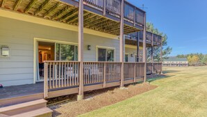 Une maison à deux étages dotée d’une terrasse en bois et d’un espace extérieur couvert.