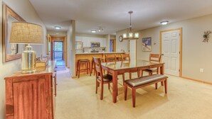 Un grand espace dédié à la salle à manger, avec une table et des chaises en bois, un banc et une lampe posée sur une console en bois.