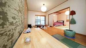 A traditional Japanese room with tatami flooring, a low table with a cushion, a futon bed, and a sliding door leading to another room. - Ryokan Asakusa-Chaka- by Tranova (Tokyo)