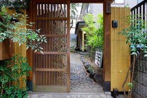 A narrow stone pathway leading to a wooden gate, surrounded by bamboo plants and a bamboo fence. - Ryokan Asakusa-Chaka- by Tranova (Tokyo)