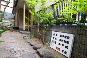 A stone pathway leading to a traditional Japanese building with a signboard displaying text. - Ryokan Asakusa-Chaka- by Tranova (Tokyo)