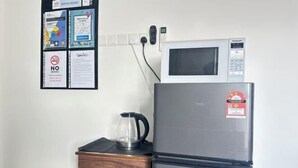 Eine Küchenzeile mit einer Mikrowelle, einem Kühlschrank und einer Kaffeemaschine auf einem Holztisch.