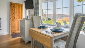 Un espace repas comprenant une table en bois, des chaises et une vue sur l’extérieur.