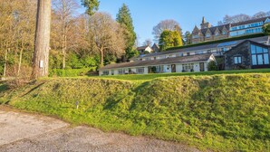 Un grand bâtiment à plusieurs étages, de style architectural traditionnel, entouré d’une végétation luxuriante et d’arbres.