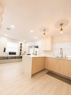 A modern kitchen with a central island, wooden cabinets, a built-in stove, and a window with a view. - •Gorgeous,Renovated & Spacious Miami Home• (Coral Gables)