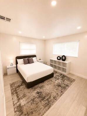 A modern bedroom with a large bed, bedside tables, a rug, and built-in shelving with decorative items. - •Gorgeous,Renovated & Spacious Miami Home• (Coral Gables)