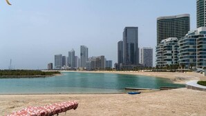 Une plage avec, en arrière-plan, le profil d’une ville, caractérisée par de hauts immeubles et une étendue de sable.