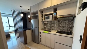 A modern kitchen with a stainless steel refrigerator, a microwave, and a sink. There is a patterned backsplash and wooden flooring.