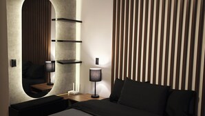 A modern bedroom with a large bed, a bedside table with a lamp, a mirror, and a wall with vertical wooden slats.