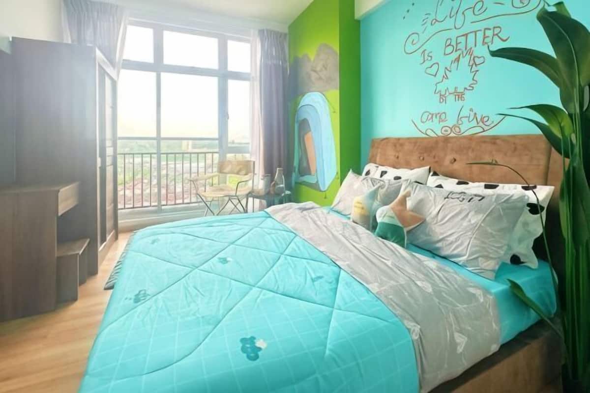 A bedroom with a bed, a desk, a chair, and a view through a window.