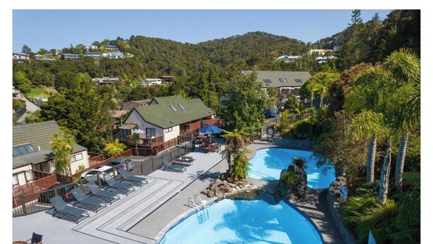A resort with two swimming pools, lounge chairs, and a view of the surrounding hills. - Paihia resort with all the amenities! (Paihia)