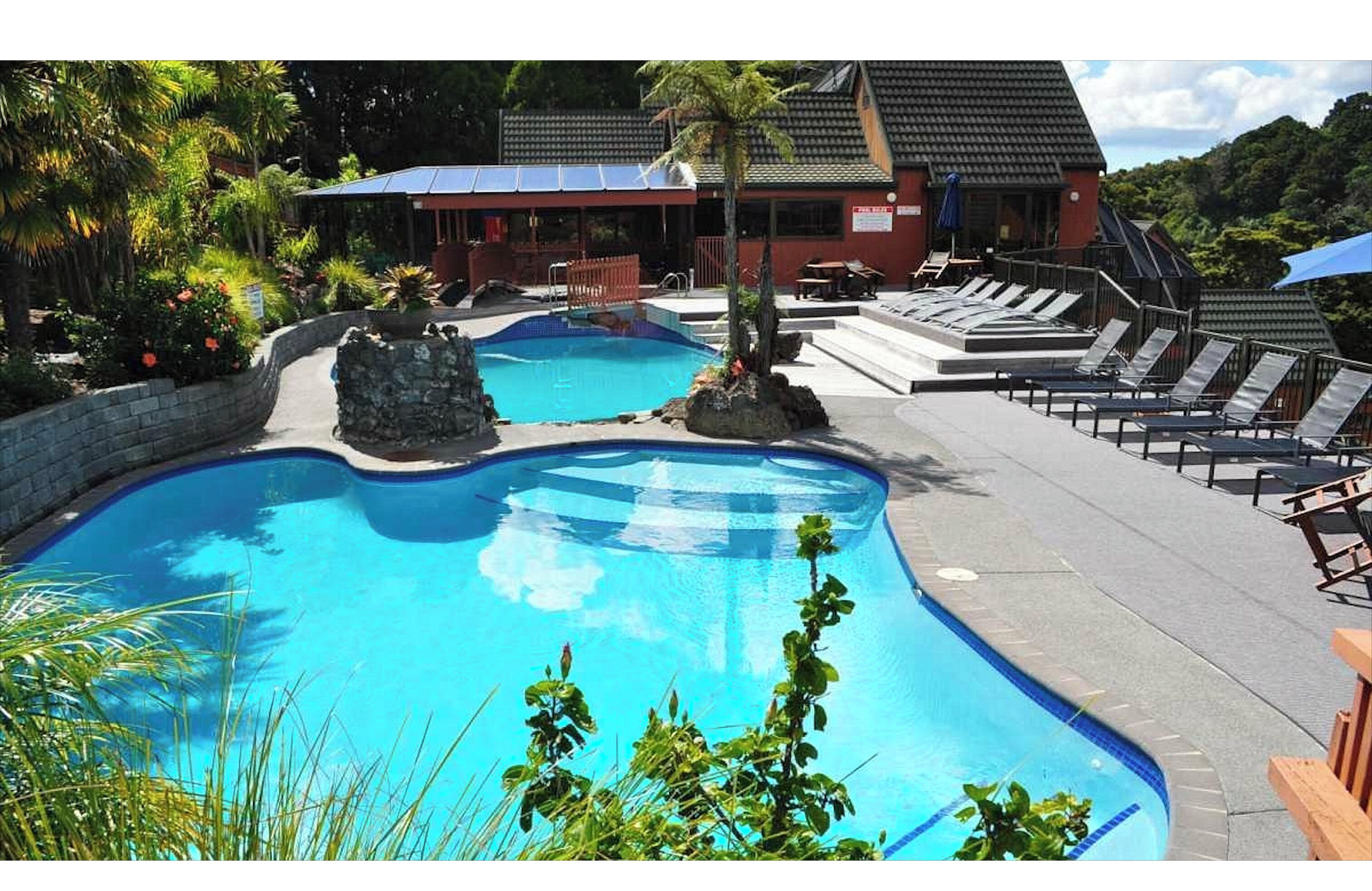 A swimming pool with lounge chairs and a building in the background.