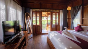 Quarto de madeira com cama, televisão e porta para varanda.