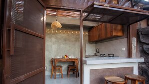 Uma cozinha compacta com armários de madeira, bancada branca e dois bancos.