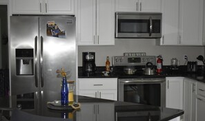 Una cocina moderna con electrodomésticos de acero inoxidable, microondas, cafetera y estufa.