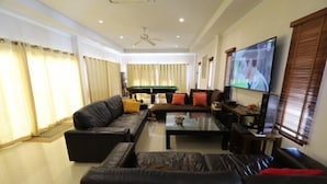 Una sala de estar con un conjunto de sofá, una mesa de centro, una televisión y una mesa de billar al fondo.