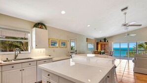 A spacious kitchen with a large island, a dining area with a view, and a balcony overlooking the ocean. - 3BR Gulf-Front Luxury with Panoramic Views (Englewood)