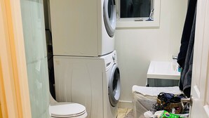 A compact bathroom with a toilet, stacked washing machine, and a small window. - Stunning 3 bedroom modern apartment in Downtown Toronto (Toronto)