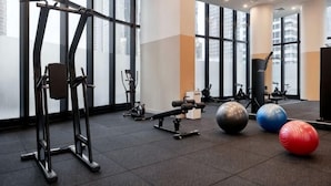 Una palestra con attrezzature per esercizi, ampie finestre e un soffitto alto.