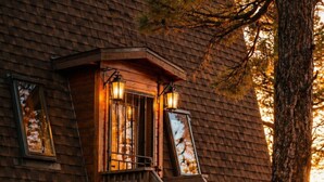 Eine Holzhütte mit Balkon, Fenster und Baum.