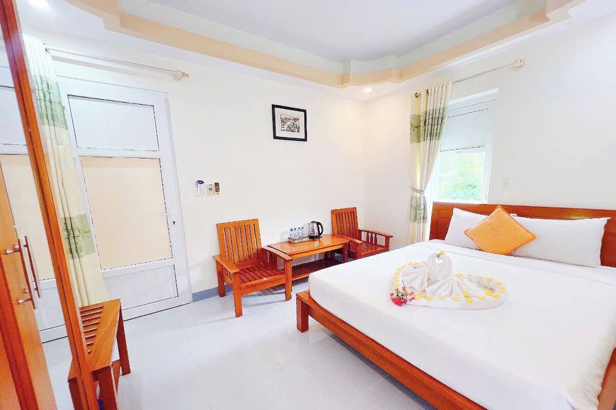 Une chambre d’hôtel avec un lit, une table, deux chaises, une fenêtre et une porte.