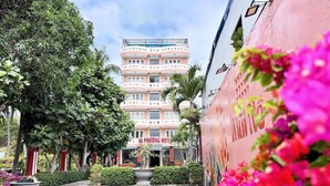 A hotel with a pink facade, a sign reading "HA PHUONG HOTEL," and a pathway leading to the entrance.