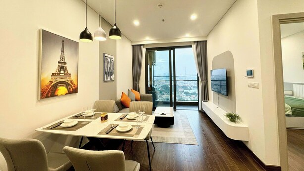 Una sala de estar moderna con comedor, un ventanal con vista a la ciudad y un televisor de pantalla plana montado en la pared.