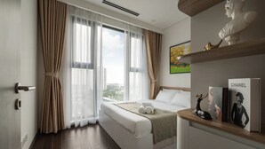 Una habitación de hotel moderna con una cama grande, vistas a la ciudad y una estantería con perfume Chanel y una escultura de busto.
