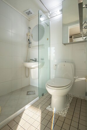 A modern bathroom with a glass-enclosed shower, a white sink, and a toilet.