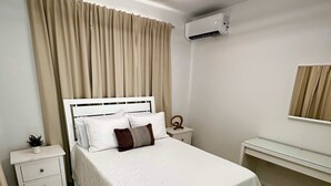Ein Schlafzimmer mit Bett, Nachttisch und einem Spiegel an der Wand.