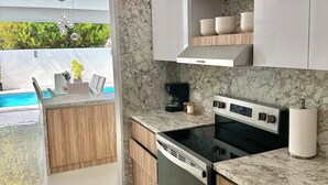 Eine moderne Küche mit Backofen, Kaffeemaschine und Blick auf einen Swimmingpool.