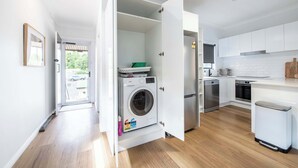 Uma cozinha moderna com armários brancos, máquina de lavar embutida e lava-louças.