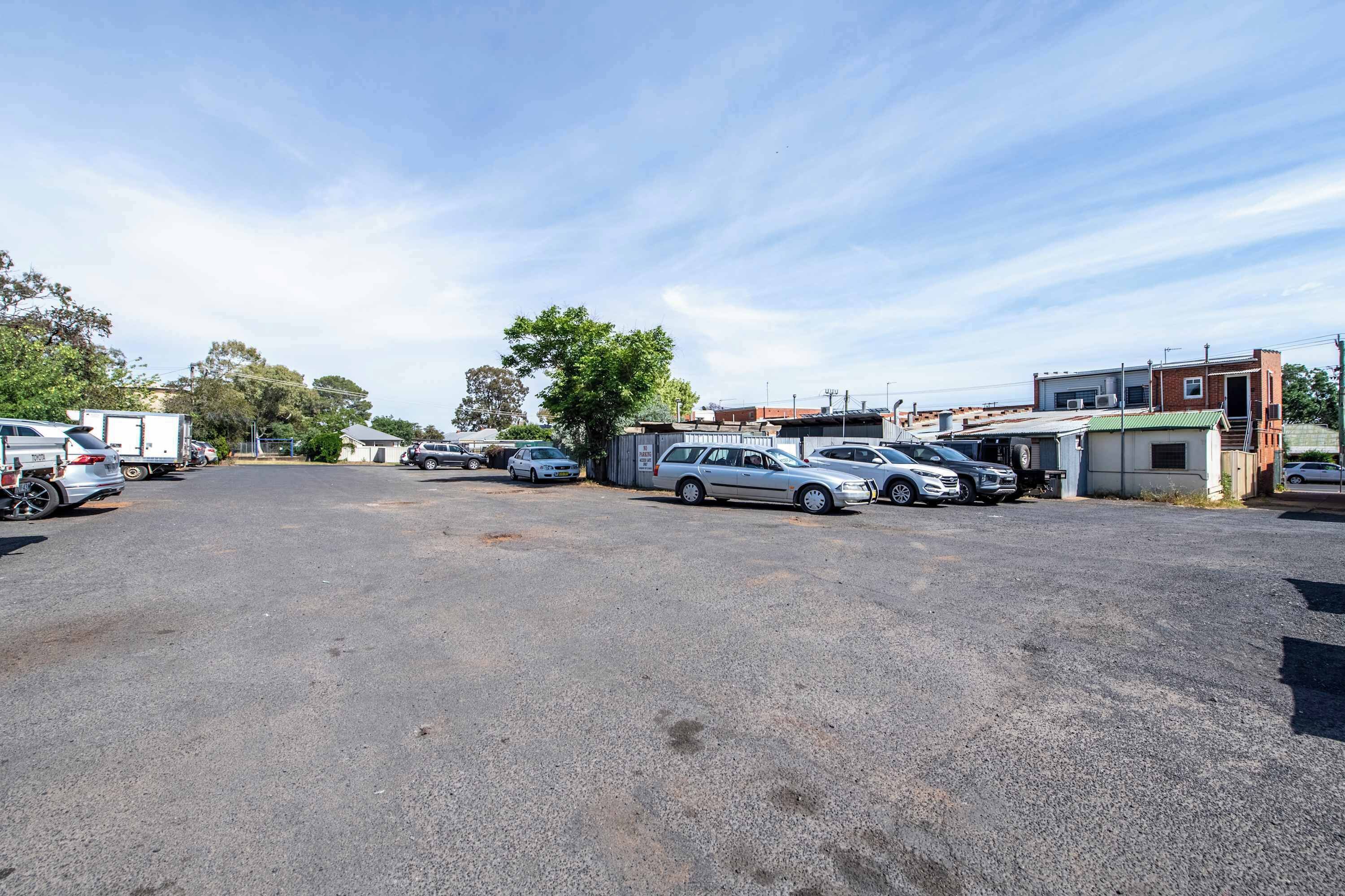 A parking lot with several cars and a building in the background.