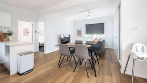 Uma sala de estar moderna com área de jantar, televisão e ventilador de teto.
