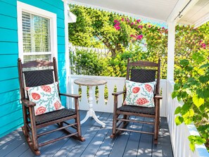A porch with two rocking chairs, a small round table, and a white picket fence. - Gorgeous 3/2 Minutes to downtown Naples & the sand (Naples)
