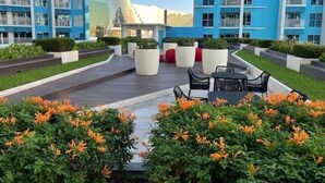 A modern outdoor area with a wooden deck, seating, and potted plants. - Perfect Seaview 2 Bedrooms, Nearby Okada Casino, Solaire Casino, Airport & MOA (Parañaque)