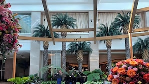 A spacious indoor atrium with a grand piano, palm trees, and a large floral arrangement. - Perfect Seaview 2 Bedrooms, Nearby Okada Casino, Solaire Casino, Airport & MOA (Parañaque)