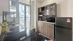 Een moderne keuken met een zwart aanrecht, houten kastjes en een zwarte koelkast.