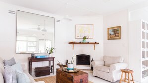 Un salon avec une cheminée, un canapé, une table basse et un grand miroir.
