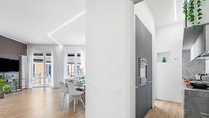 A modern kitchen with a built-in oven and a dining area with a white table and chairs.