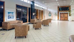 Un'ampia hall con diverse zone relax, una grande finestra e una parete decorativa.