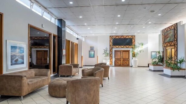 Un'ampia hall con diverse zone relax, un'entrata spaziosa e pannelli decorativi alle pareti.